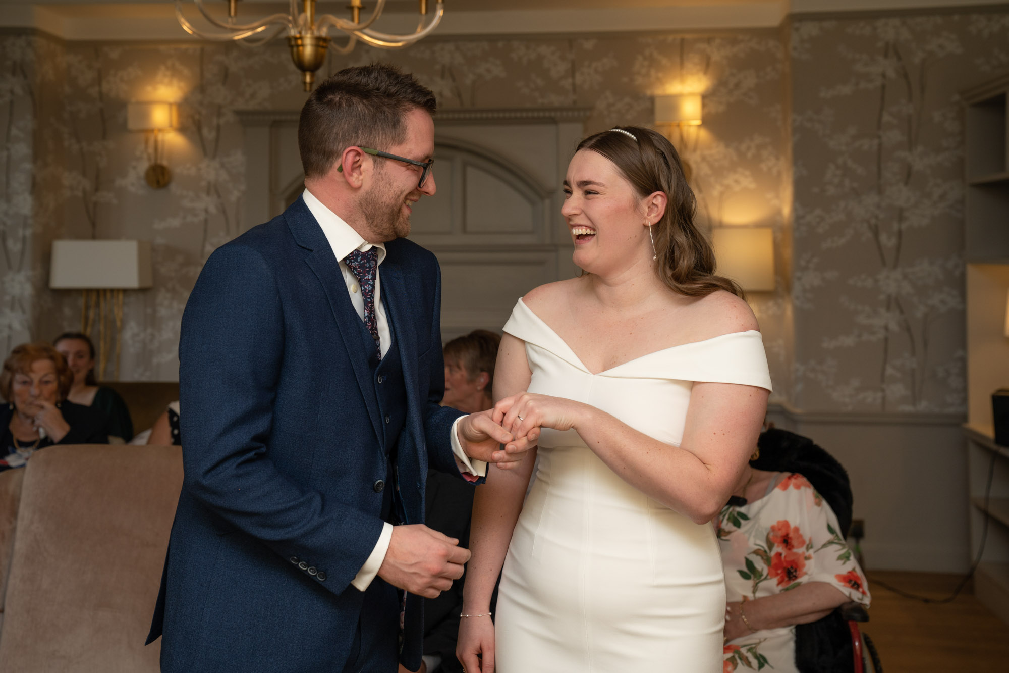 Bride and groom laughing together during the ring exchange at their Crag Wood ceremony, guests smiling in the background