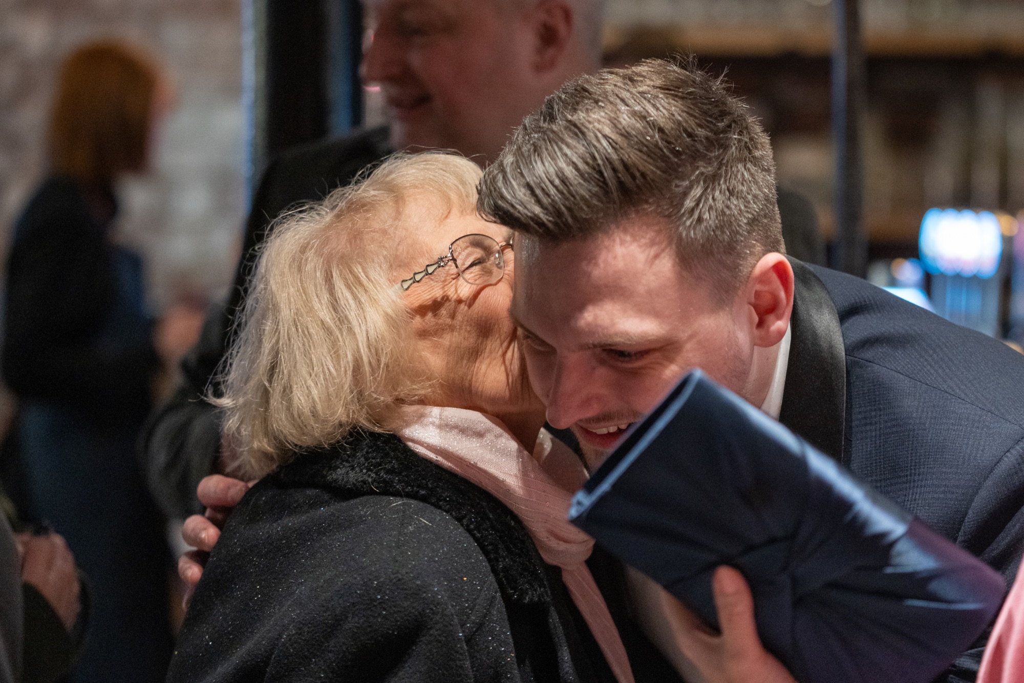 A guest hugging the groom warmly before the ceremony in a brick-walled bar
