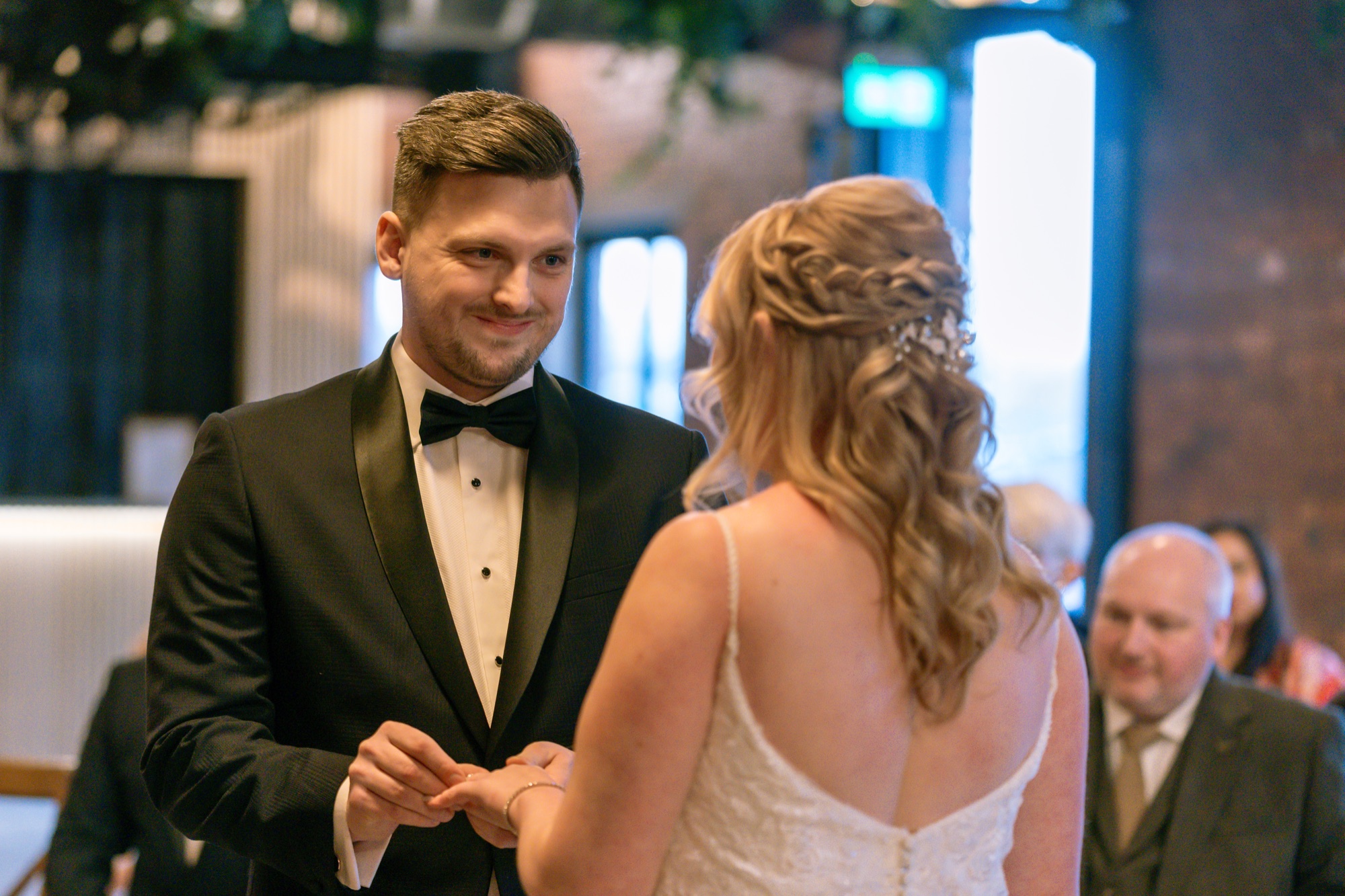 Close-up of the groom placing the ring on the bride's finger during the ceremony