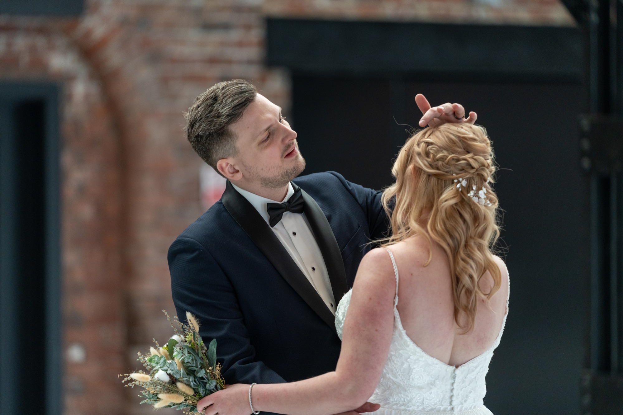 The groom gently adjusting the bride's hair during a quiet moment together