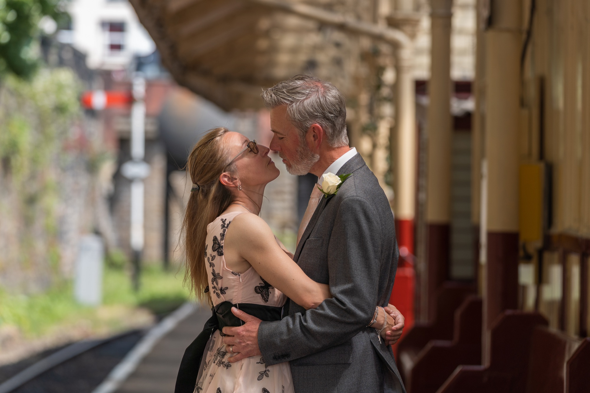 Bride and groom sharing a forehead kiss on the platform, golden light through the station canopy columns
