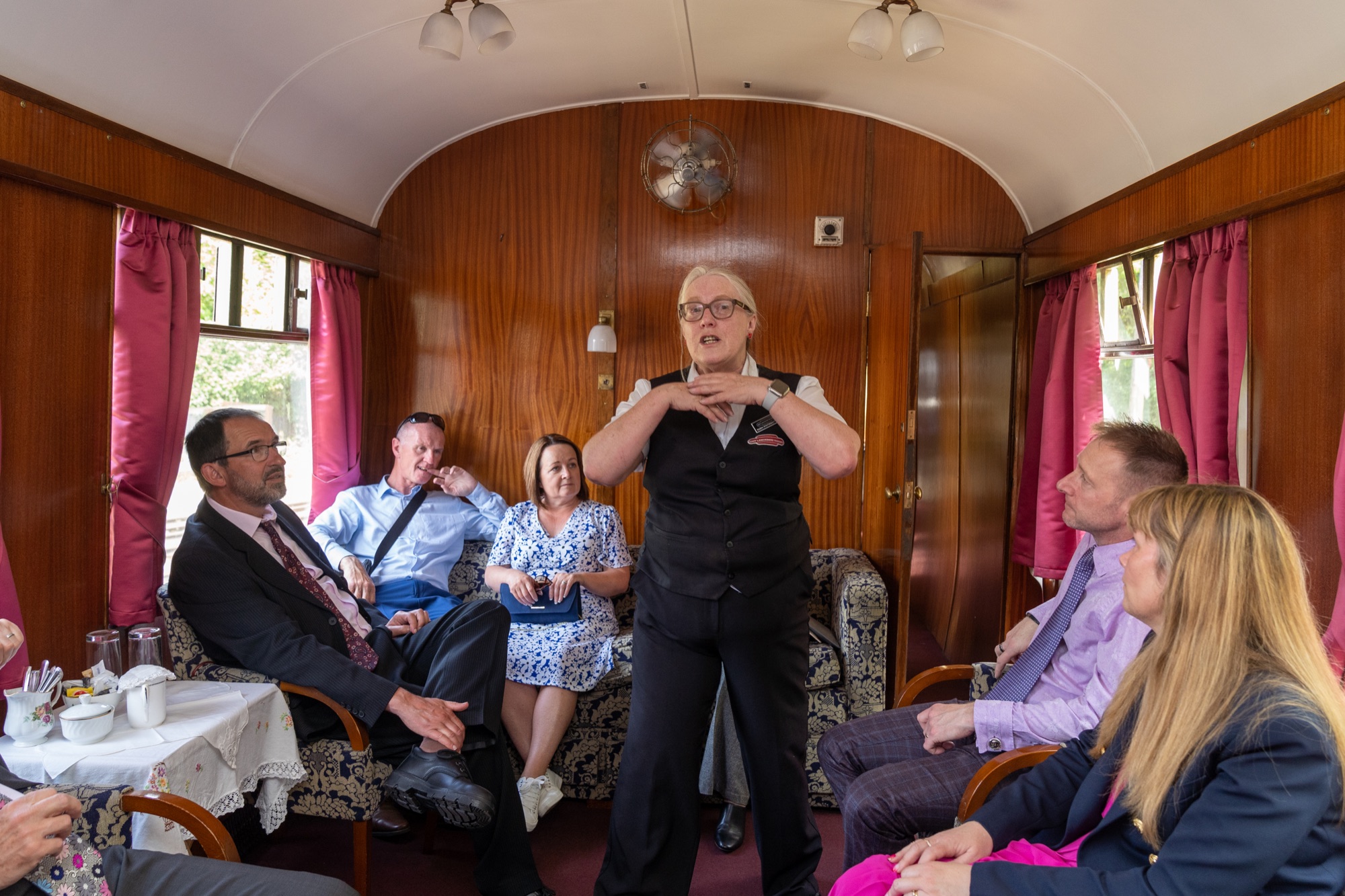 Guest giving a speech standing in the vintage railway carriage while others listen from their seats