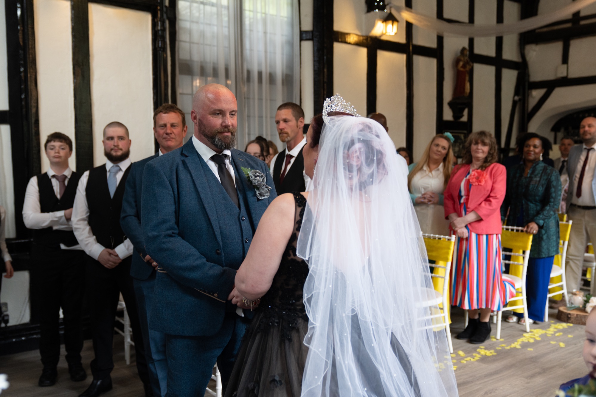 The bride and groom hold hands during their vows in front of family and friends.