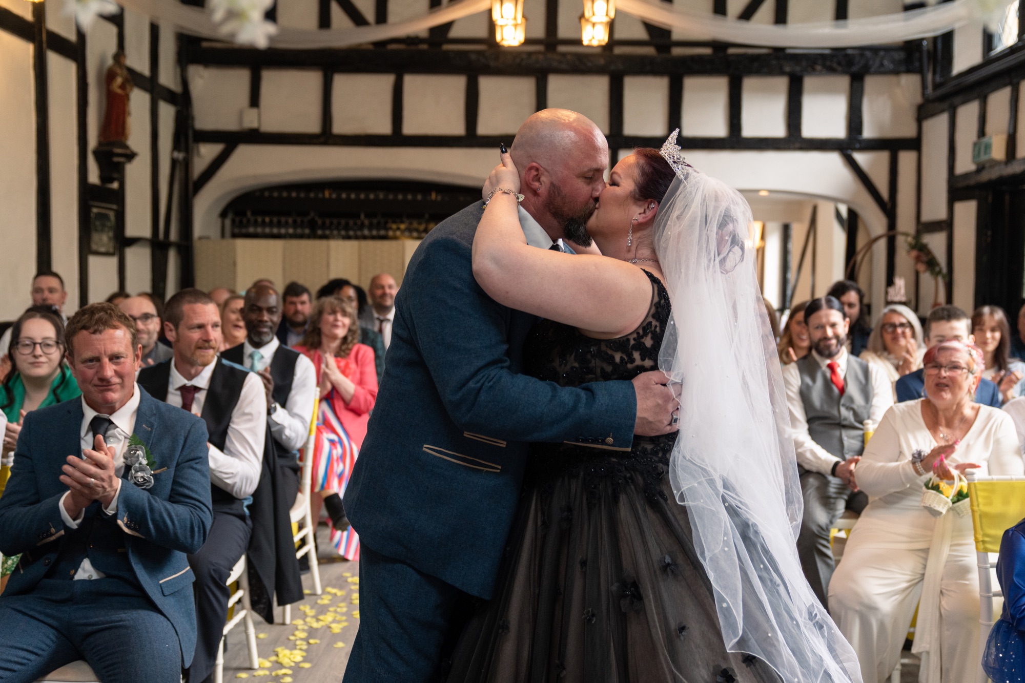 The newlyweds share their first kiss as guests applaud inside the ceremony room.