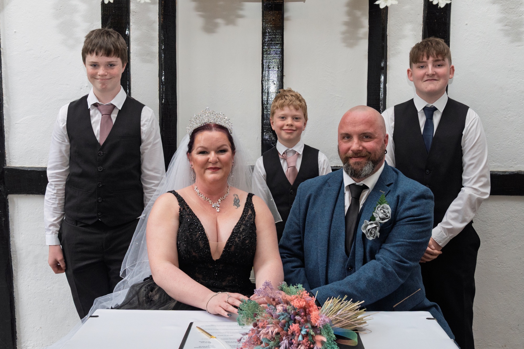 The newly married couple sign the register, joined by their sons.