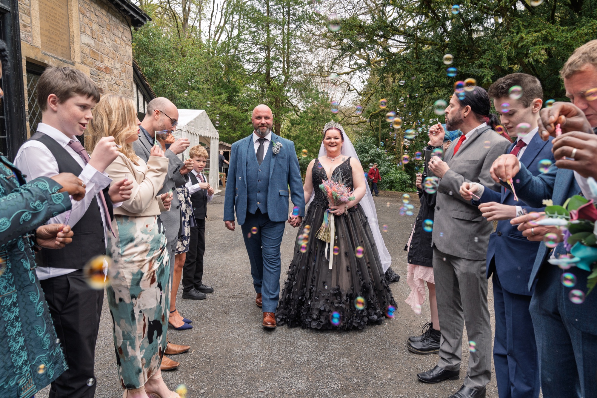 The couple walk out through a shower of bubbles and confetti from their guests.