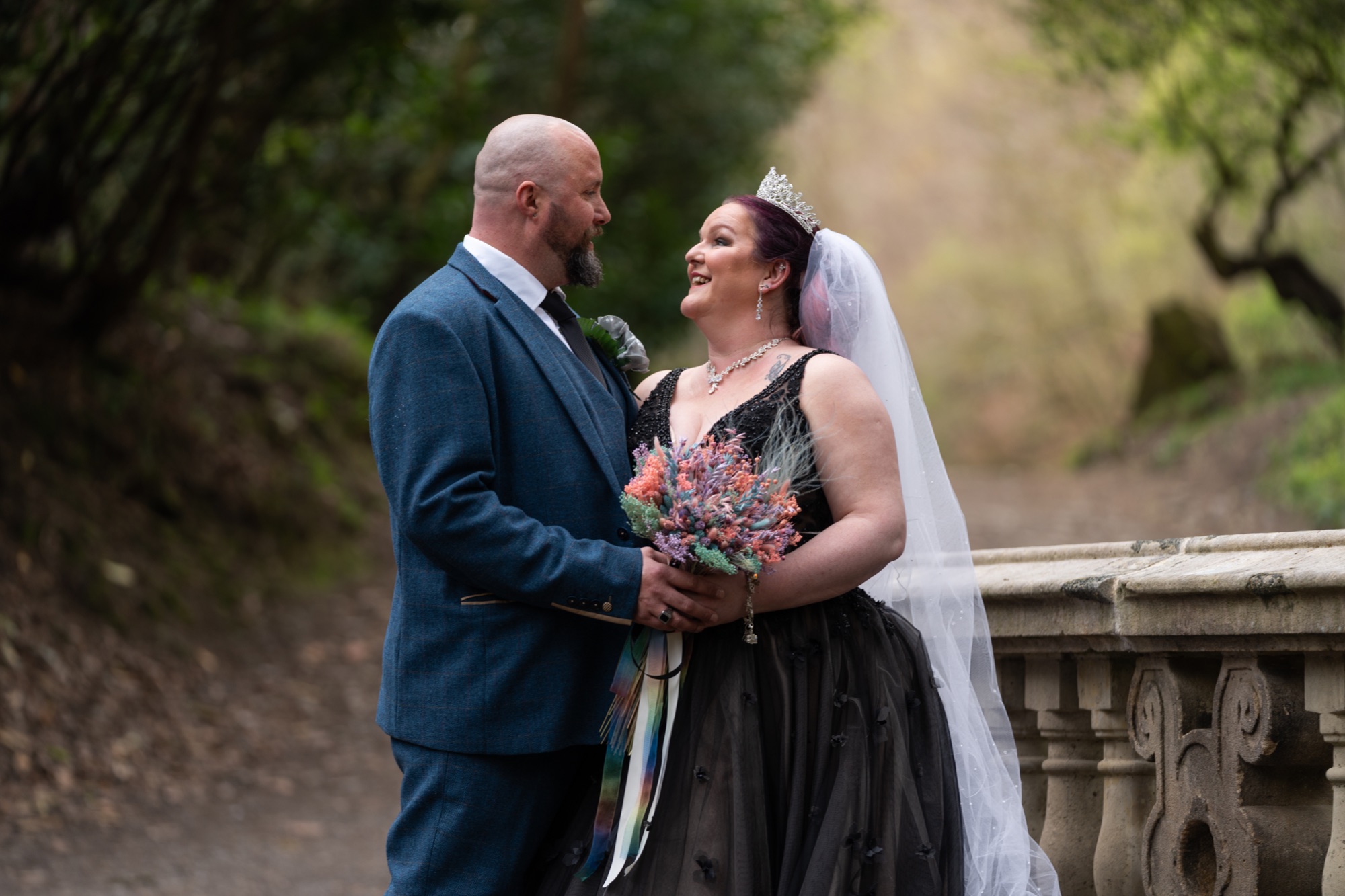 The newlyweds embrace during their portrait session in the woods, bride holding her bouquet.