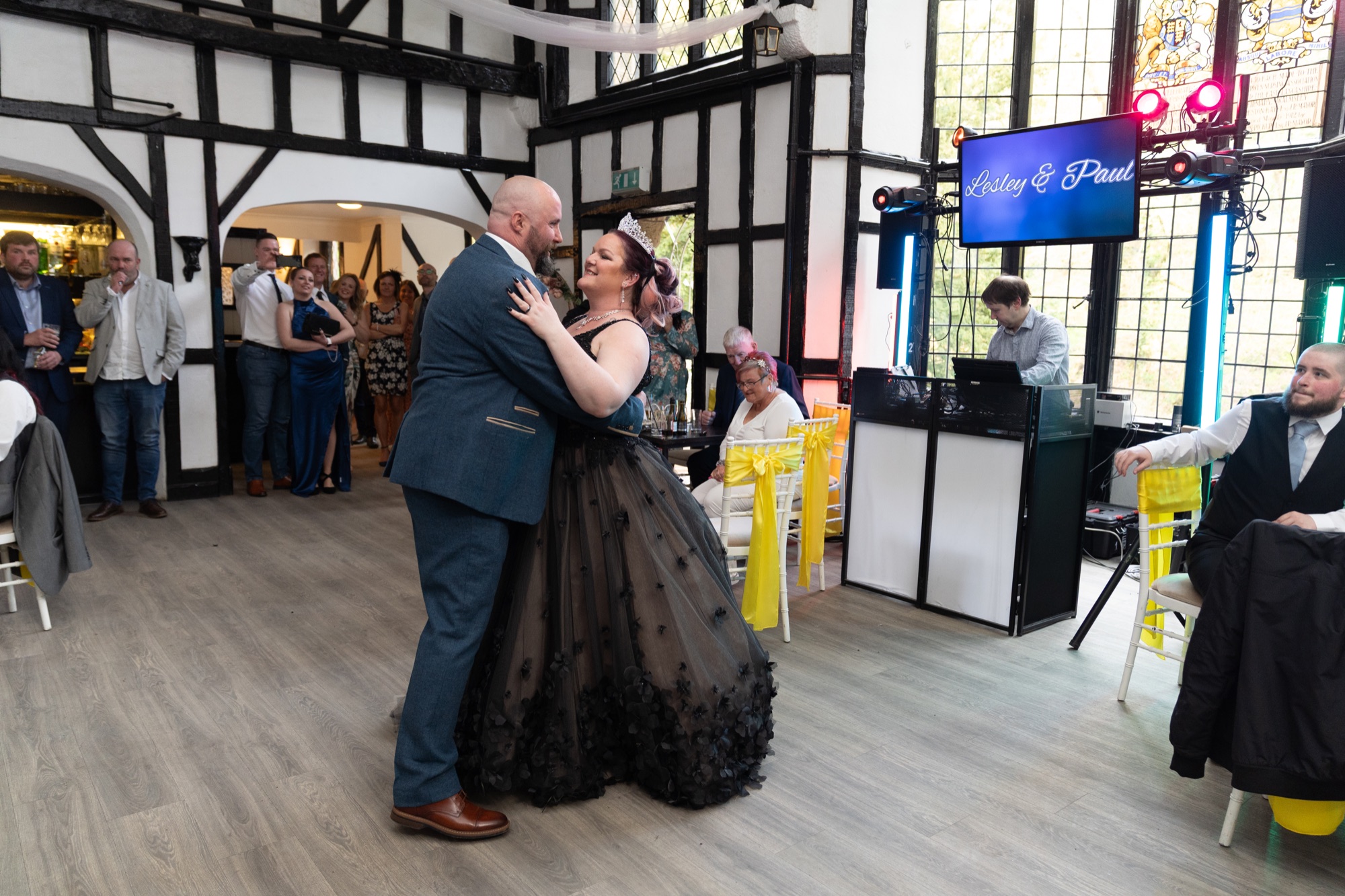 The newlyweds share their first dance beneath a screen reading their names at Olde England Kiosk.