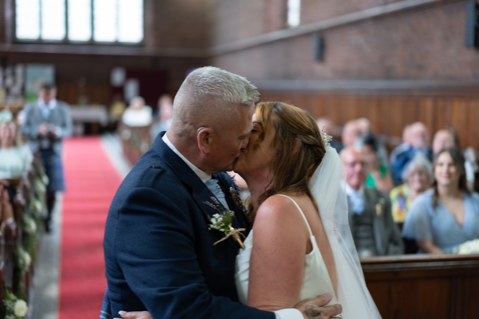 Bride and groom share their first kiss at the altar in front of guests