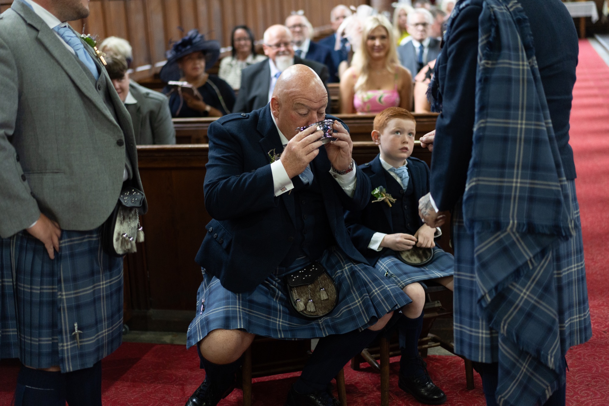 Guest in a kilt wiping away tears during an emotional moment in the ceremony