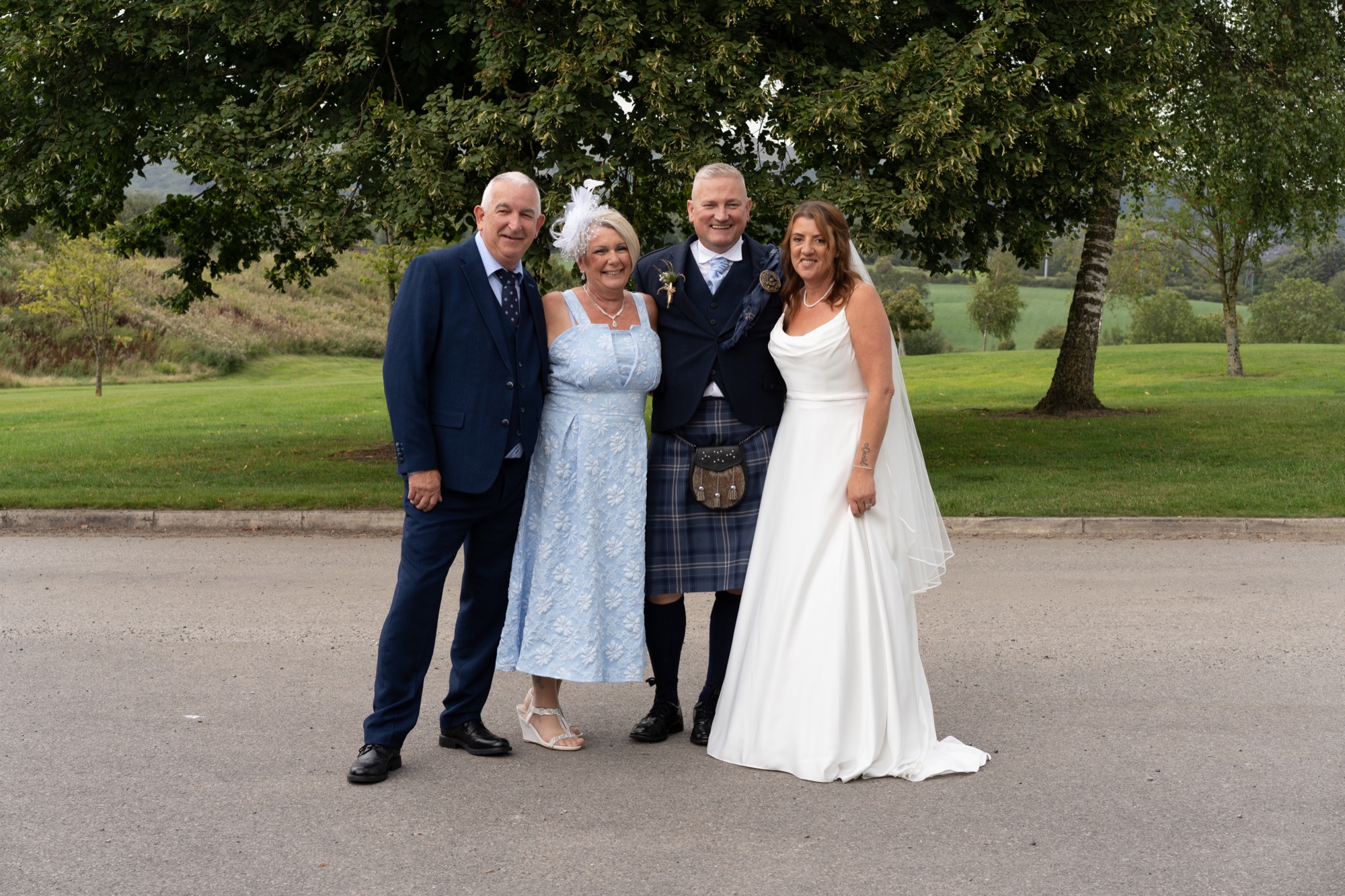 Bride and groom with family posing together on the lawn at The Hawthorns