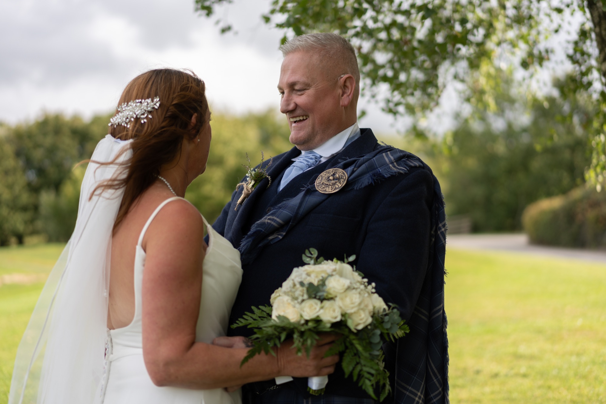Bride and groom standing close together in profile on the grounds