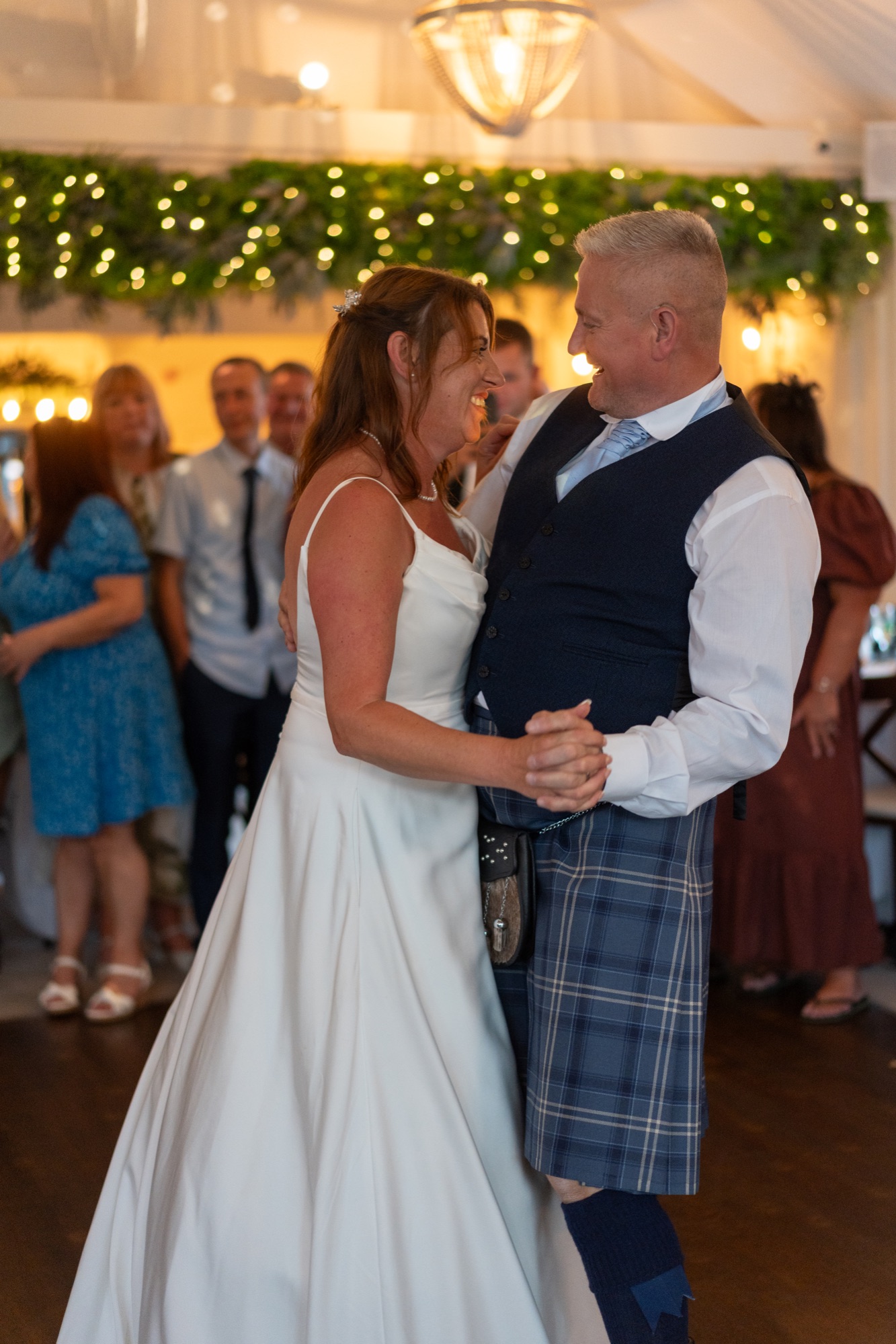 Bride and groom sharing their first dance under fairy lights