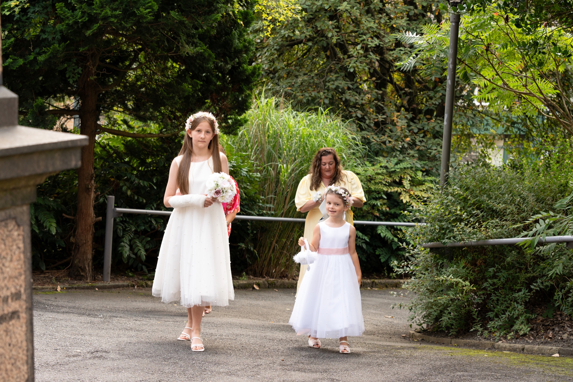 Two flower girls in white dresses and flower crowns arriving at the church