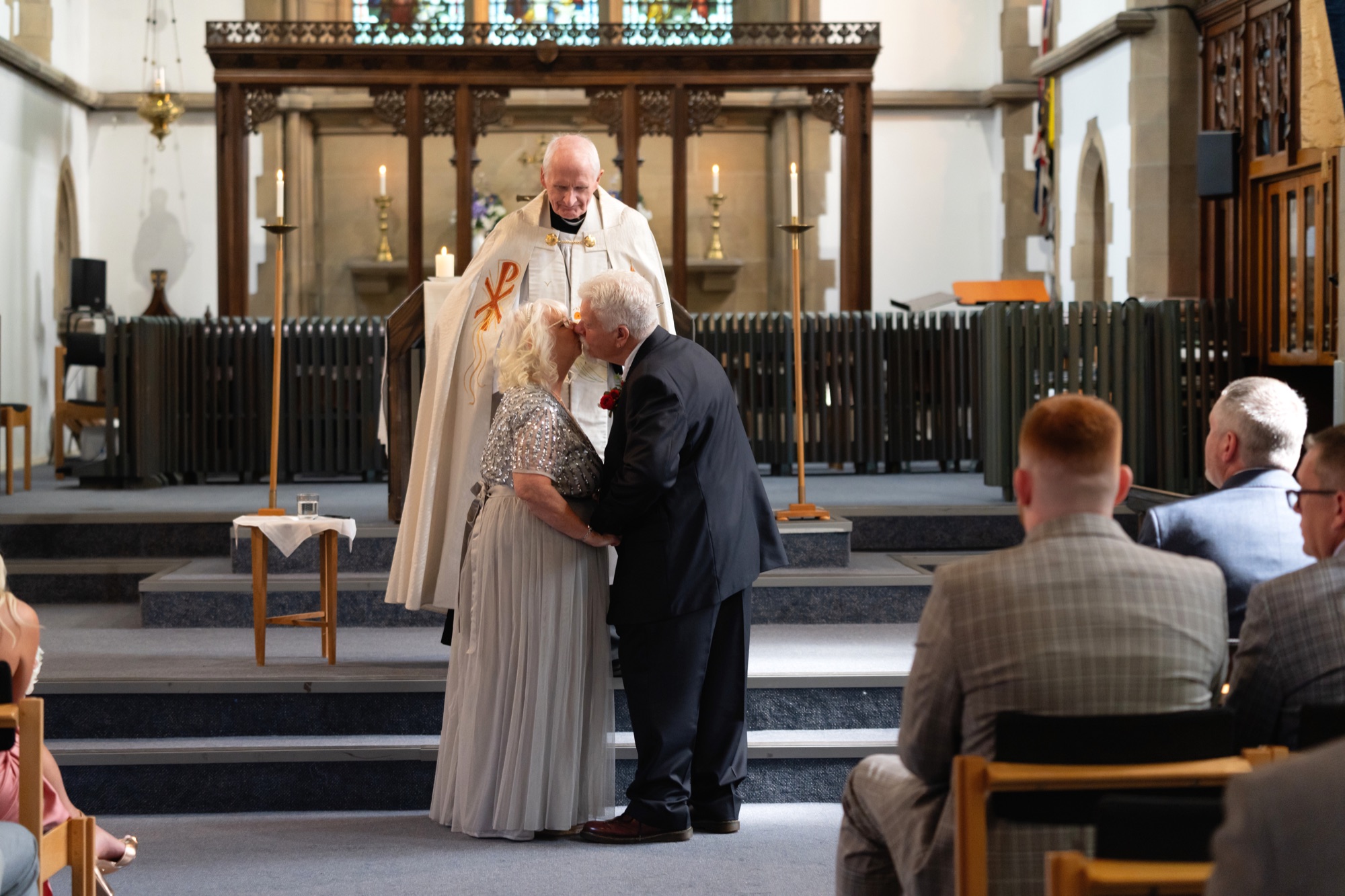 The bride and groom share their first kiss as a married couple at the altar