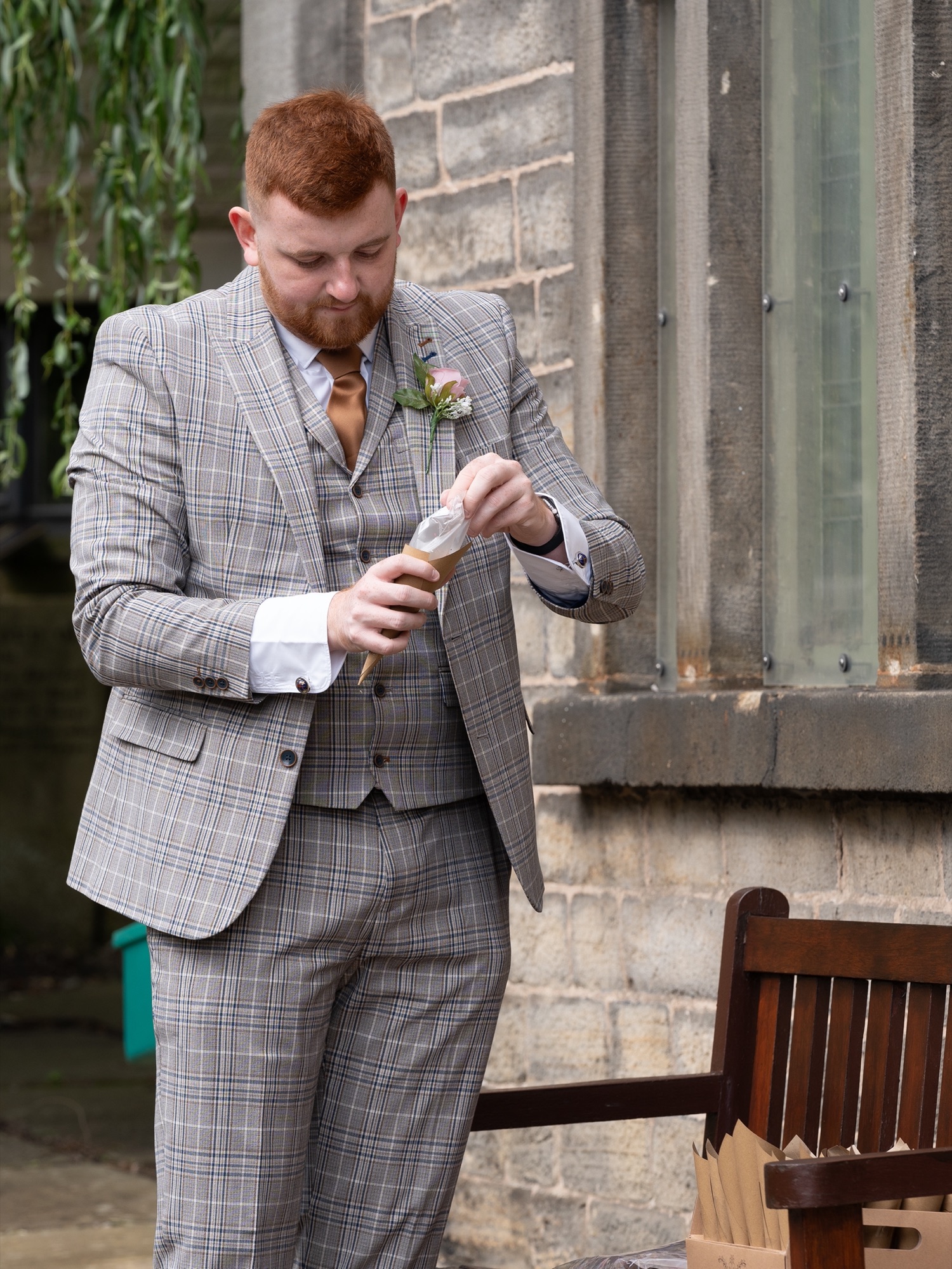 A guest opening a cone of confetti outside the church ahead of the couple's exit