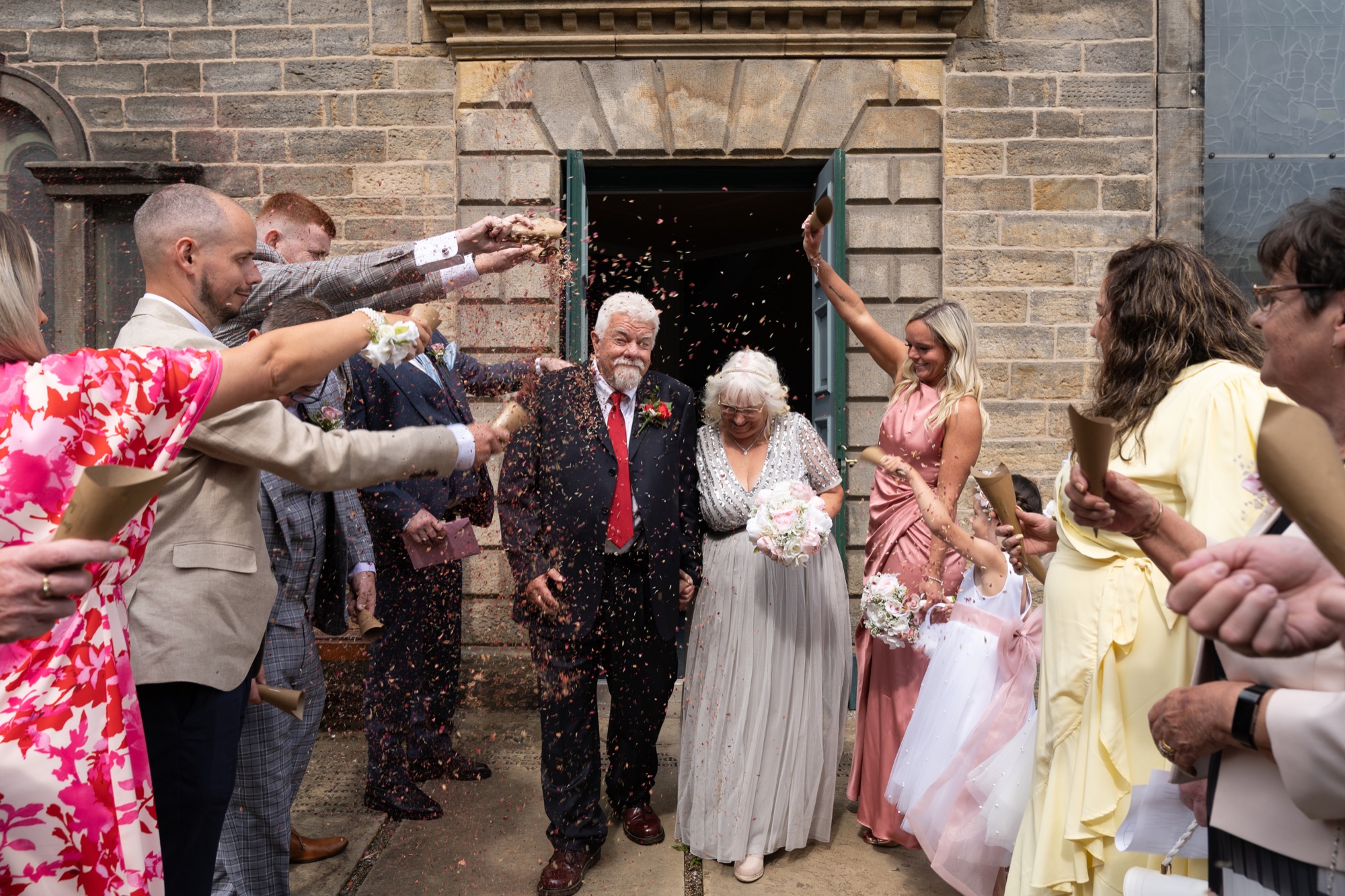 Guests throwing confetti over the bride and groom as they leave the church