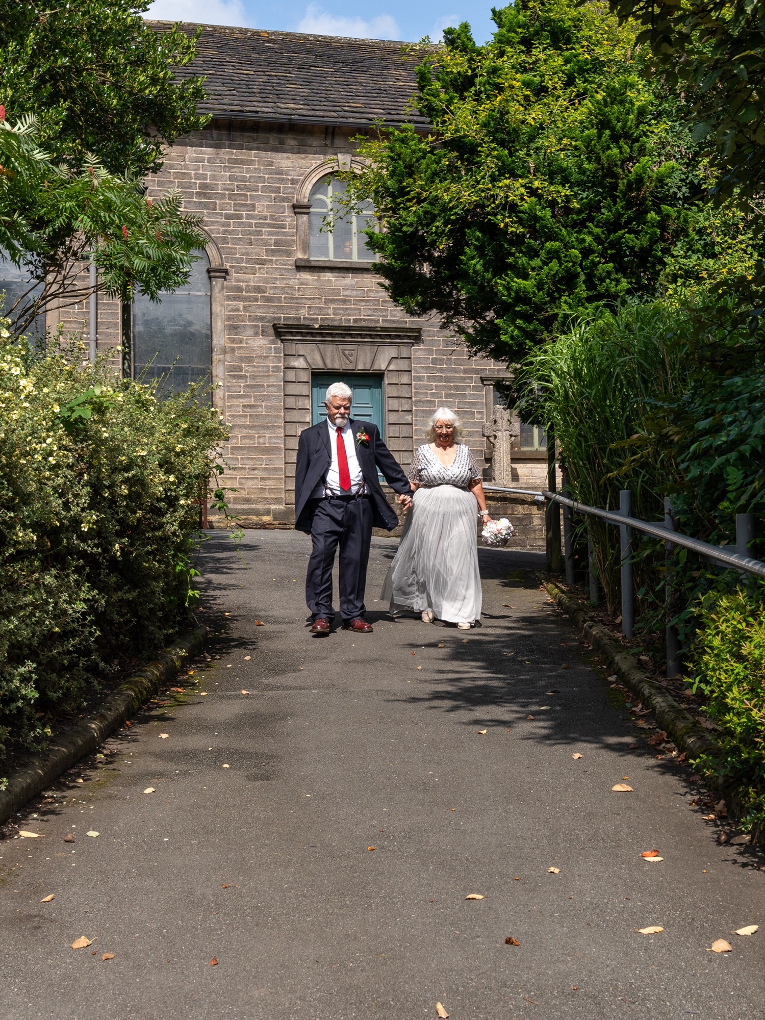 The bride and groom walking hand in hand along a garden path after the ceremony