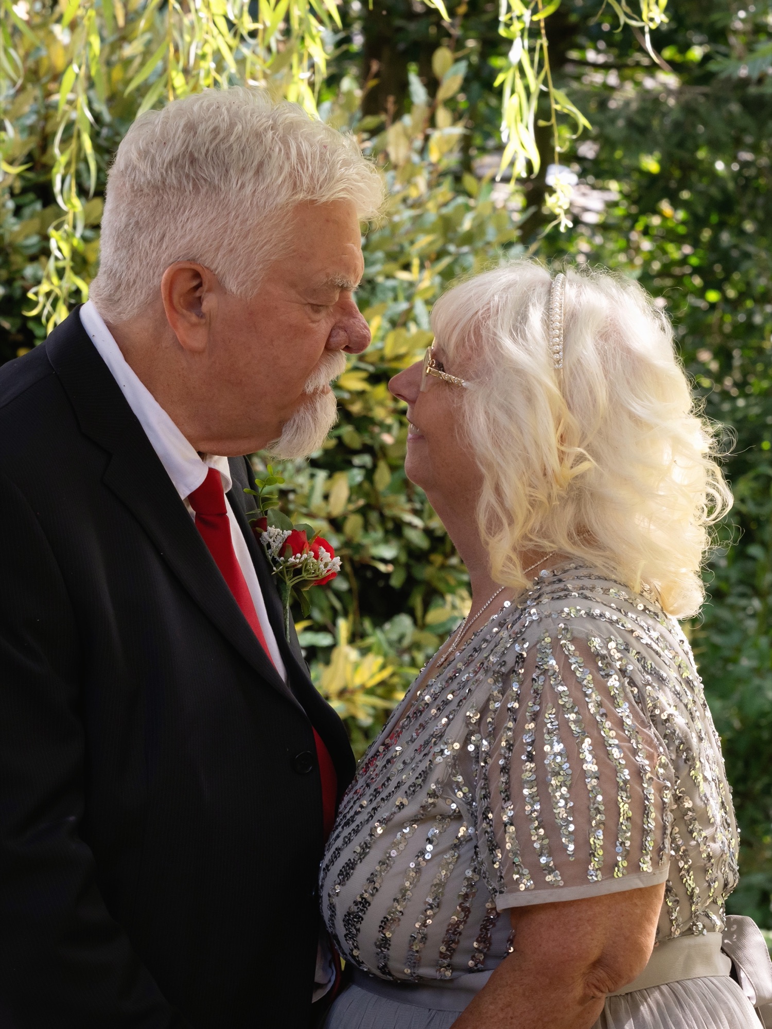 An intimate, nose-to-nose moment between the bride and groom in the garden