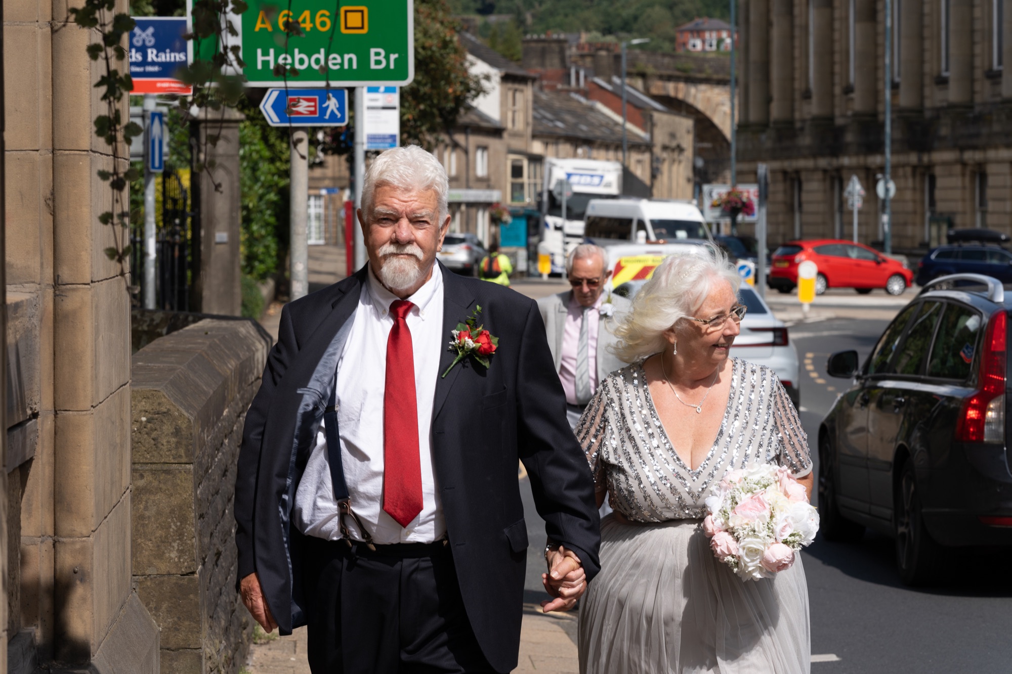 The bride and groom walking hand in hand through the streets of Todmorden